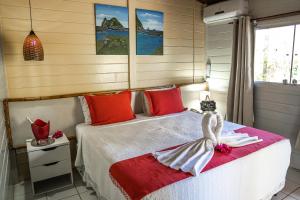 Schlafzimmer mit einem Bett mit roter und weißer Bettwäsche in der Unterkunft Pousada Sueste in Fernando de Noronha