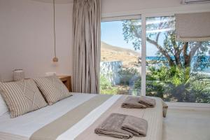 een slaapkamer met een bed en een groot raam bij Unforgettable Tinos beach houses complex in Agios Ioannis
