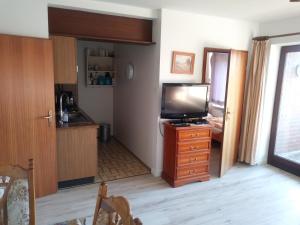 a living room with a kitchen and a flat screen tv at Deichblick in Friedrichskoog