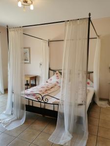 NeefにあるWeingut Amlinger&Sohnのベッドルーム(白いカーテン付きの天蓋付きベッド1台付)
