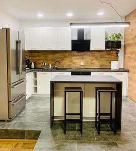 a kitchen with white cabinets and a counter with stools at Apartament Arte Povera in Słubice