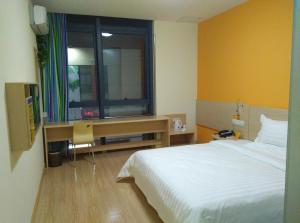 蘇州的住宿－7天酒店·苏州望亭明珠商业广场店，一间卧室配有一张床、一张书桌和一个窗户。