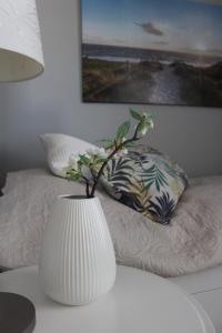 a white vase with a plant in it on a table at Spuren im Sand in Sankt Peter-Ording