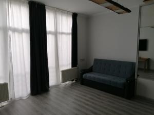 a living room with a blue couch in front of windows at Palm apartment studio Riga in Rīga