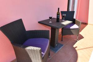 a table with a bottle of wine and two wine glasses at Apartments Villa Miranda in Vodice