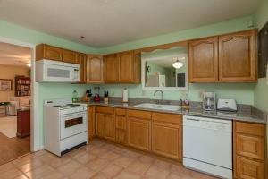 a kitchen with white appliances and wooden cabinets at Across from Dollywood w FREE Dollywood ticket, pets ok wfee, arcade, hot tub in Pigeon Forge