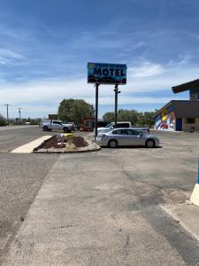 ein Motelschild und ein Auto auf einem Parkplatz in der Unterkunft Four Winds Motel & RV Park in Carrizozo