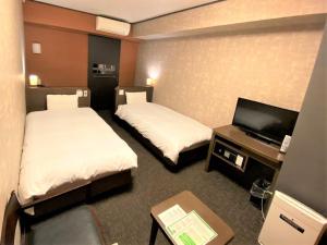 a hotel room with two beds and a flat screen tv at Dormy Inn Premium Kyoto Ekimae Natural Hot Spring in Kyoto