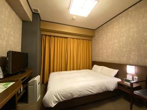 a bedroom with a bed and a desk and a television at Dormy Inn Premium Kyoto Ekimae Natural Hot Spring in Kyoto