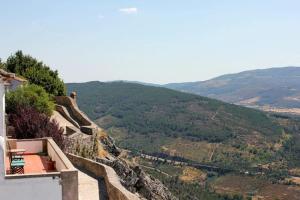 uma pessoa sentada numa saliência com vista para um vale em Casa da Arvore em Marvão