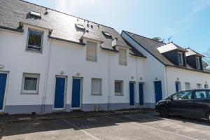 a white building with blue doors and a car at KER HEDWIGE in Carnac