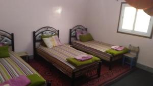 2 Betten in einem Zimmer mit grünen Kissen in der Unterkunft Auberge De la Jeunesse in Ouarzazate