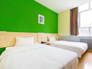 two beds in a room with a green wall at 7Days Inn Xining Kunlun Road Cross in Xining