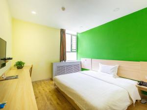 a bedroom with a large bed with a green wall at 7Days Inn Xining Kunlun Road Cross in Xining