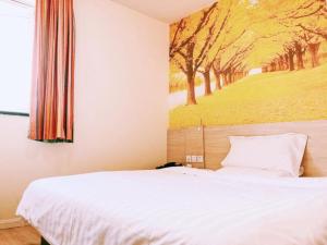 une chambre avec un lit avec un tableau sur le mur dans l'établissement 7Days Inn Huaibei Zhongtai Plaza Wanda Studios, à Huaibei