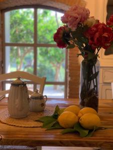 a table with lemons and a vase of flowers and a vase at Il giardino dei limoni in Suvereto