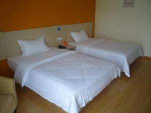 twee bedden naast elkaar in een kamer bij 7Days Inn Suzhou Wangting Pearl Plaza in Suzhou