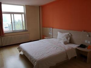 1 dormitorio con 1 cama grande y pared de color naranja en 7Days Inn Yantai Development Zone Beach, en Yantai