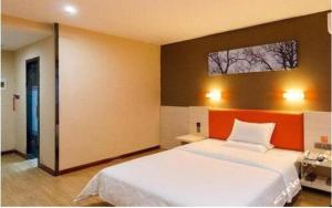 Zhuangheにある7 Days Premium Dalian Zhuanghe Huanghai Avenueのベッドルーム1室(オレンジ色の壁の大きな白いベッド1台付)