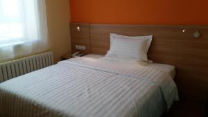 a bedroom with a white bed with an orange wall at 7Days Inn Harbin Pioneer Road Xilong Market in Harbin