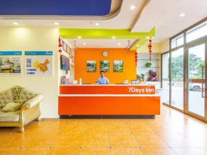 a man standing at a pays inn counter in a lobby at 7Days Inn Xining Kunlun Road Cross in Xining