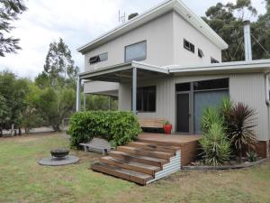 a white house with a wooden deck in the yard at Dacelo in Halls Gap