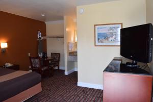a hotel room with a bed and a flat screen tv at Seaside Inn Monterey in Seaside