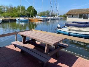 a wooden picnic table sitting on a dock with boats at Marinaparcs Almere in Almere
