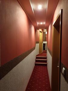 einen Flur mit roten Teppichen und Treppen in einem Gebäude in der Unterkunft Waldhotel Lemberg in Hagen
