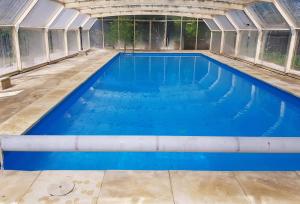 a swimming pool inside a greenhouse with blue water at Au coeur de nos campagnes in Lachapelle-Saint-Pierre