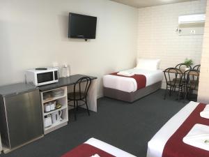 a hotel room with two beds and a tv at Atlas Motel in Dubbo