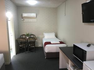 a small room with a bed and a table and chairs at Atlas Motel in Dubbo