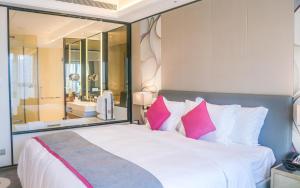 a bedroom with a large white bed with pink pillows at Crowne Plaza Hangzhou Qiantang in Hangzhou