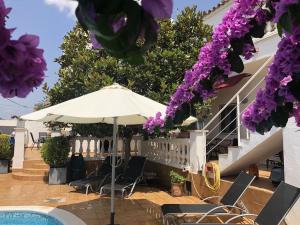 a patio with an umbrella and chairs and purple flowers at Casa Pani in Empuriabrava