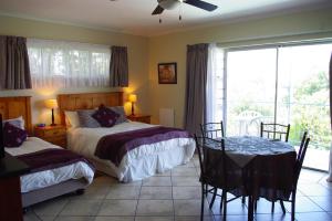 um quarto com 2 camas, uma mesa e uma janela em Aqua Marine Guest House em Port Elizabeth