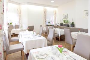 ein Esszimmer mit Tischen und Stühlen mit weißen Tischdecken in der Unterkunft Hotel Engelbert in Iserlohn