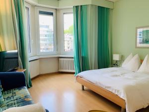 ein Schlafzimmer mit grünen Vorhängen, einem Bett und einem Sofa in der Unterkunft Apartments zum Löwen in Luzern