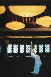 una mujer con un vestido blanco sentada en una pared en Dali Sky Valley Heritage Boutique Hotel, en Dali
