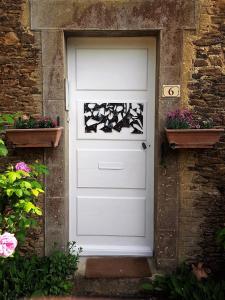 a white door in a brick building with two plants at B&B L'Atelier du Presbytère in Saint-Maugan