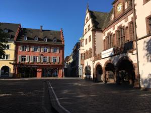 an empty street with buildings and a clock tower at Bobbele Freiburg Zentrum in Freiburg im Breisgau