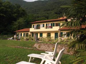 two white chairs sitting in front of a house at Villa Oliveto apartments in Oliveto Lario