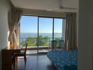 une chambre avec un lit et un bureau et une grande fenêtre dans l'établissement Bella Vista Vung Tau, à Vung Tau