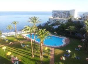 ośrodek z basenem, palmami i oceanem w obiekcie Torre de la Roca INDUSTRIAL69 w mieście Torremolinos