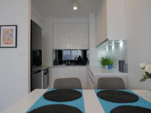 una cucina con armadi bianchi, tavolo e sedie di Apartament NA KLIFIE a Słupsk