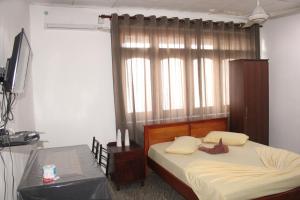 a bedroom with a bed and a tv and a window at Hillstreet Villa in Dehiwala