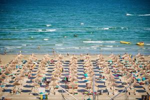 - une plage avec de nombreux parasols et des personnes dans l'eau dans l'établissement Rusty Sands apt Spa n Pools Beach resort, à Mamaia Nord – Năvodari