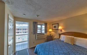 a bedroom with a bed and a balcony at Sands By The Sea Motel in York Beach