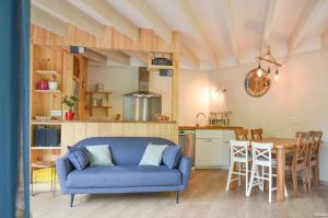 a living room with a blue couch and a kitchen at Eco logis le colibri in Le Teich