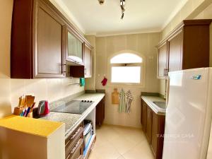 a kitchen with wooden cabinets and a white refrigerator at Cozy Family 3 BR apartment by the sea in Marsa Alam City