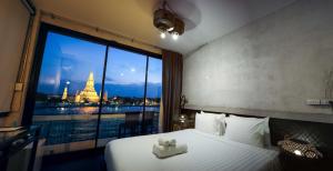 a bed with a teddy bear on it in a room with a window at Inn a day in Bangkok